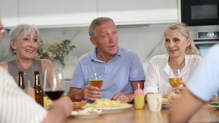 Wall Mural - Group of happy people of different ages at family dinner drinking and chatting at table in kitchen