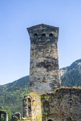 Wall Mural - Medieval defensive stone tower with loopholes. Old walls. Trees, green grass and bushes.