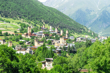 Wall Mural - View of the City of Mestia. Medieval defensive stone towers with loopholes, residential houses. Trees, hills covered with bushes and trees.