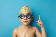 © LimeSky - Young swimmer in gear on blue background Child points promoting Boy studies swimming at sports school With space for text