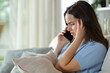 © Antonioguillem - Worried woman attending phone call at home