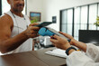© DragonImages - Man paying with smartphone for sport training while administrator holding terminal