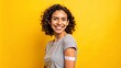 © DigitalArt Max - A smiling young adult with a medical patch on their arm, posed against a bright yellow background, conveying a sense of vaccination and wellness.