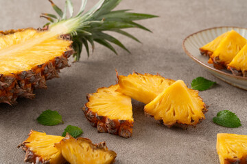 Wall Mural - Fresh sliced and cut pineapple pieces on gray table background.