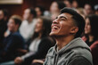 © frankb - Young man wearing a hoodie laughing in the audience