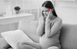 © Prostock-studio - Headache During Pregnancy. Expectant Woman Having Severe Migraine Massaging Temples Sitting On Sofa Indoor.