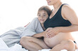© puhimec - A pregnant woman and her teenager daughter are sitting on the bed.