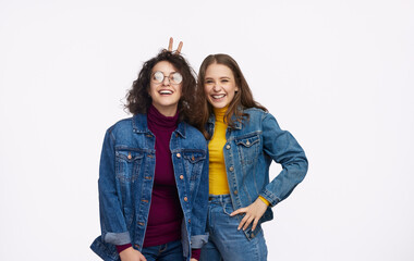 Wall Mural - Two young women laughing and enjoying each other's company while wearing denim jackets. Concept of friendship and joy.