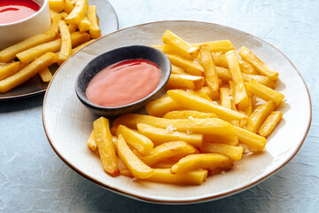 French fries with tomato sauce, two plates of delicious potato chips on a table