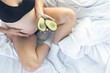 © puhimec - Pregnant woman holding avocado in bed, health and maternity concept.