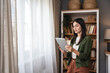 © Srdjan - Real estate agent with tablet pc looking through window. Young business woman working at home, using device gadget. Successful professional occupation graphic designer female taking a break from work.