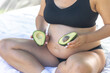 © puhimec - Pregnant woman holding avocado, health and maternity concept.