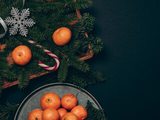 Christmas card with tangerines. Plate with tangerines with Christmas decorations