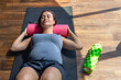 © puhimec - Pregnant woman in the gym on a mat with a massage roller.