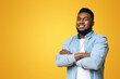© Prostock-studio - Confident black millenmial man standing with his arms crossed, smiling and looking at camera, yellow studio background with copy space