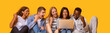 © Prostock-studio - Group of international students celebrating success over yellow background, checking exam results online, panorama