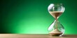 © STDG - Hourglass with sand running through isolated on vibrant green background, time, passing, deadline, measurement