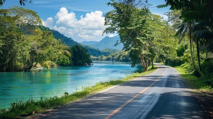 Wall Mural - Create an AI image of a picturesque road along a river, with clear blue water and lush greenery, emphasizing tranquility.