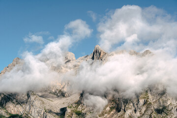 Mountains partially covered by clouds under a clear blue sky during daylight