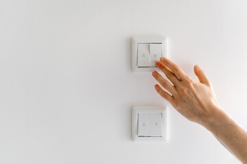 Woman hand reaching for white light switch