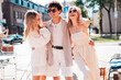 © halayalex - Young three stylish friends posing in the street. Fashion man and two cute female dressed in casual summer clothes. Smiling models having fun. Cheerful women and guy outdoors, in sunny day, sunglasses