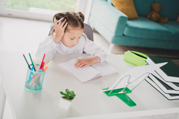 Wall Mural - Photo portrait of cute small schoolgirl minded tired do homework home education concept school interior