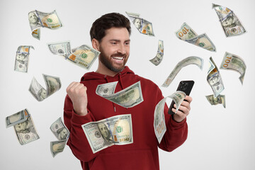 Canvas Print - Happy man using mobile phone on white background. Money flying out of device