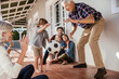 © Marko Geber - Multigenerational family playing soccer on house porch