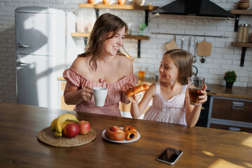 Happy woman and kid having breakfast at home