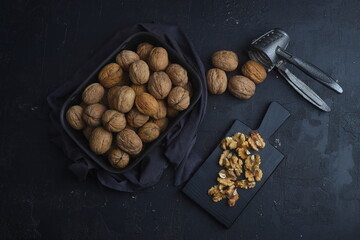 broken walnuts and nutcracker on black background