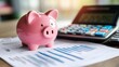 © 69 - Pink piggy bank placed next to a calculator and financial documents, representing budgeting and financial planning