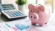 © 69 - Pink piggy bank placed next to a calculator and financial documents, representing budgeting and financial planning