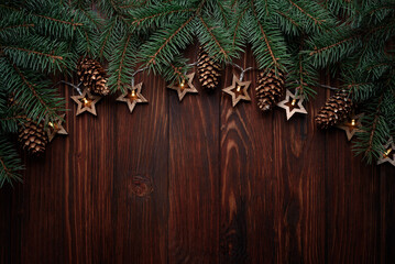 Wall Mural - Christmas background with fir branches, cones and star shape lights on dark wooden board. Top view. Copy space. Xmas decoration