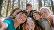 © VK Studio - A group of friends huddle together, smiling joyfully in the woods, capturing a lively and carefree moment.