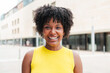© Jose Calsina - Close up individual portrait of one teenage african american girl smiling and looking at camera outside. A young adult woman staring front and laughing. Afro female gazing with friendly expression