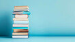 © Anthichada - A stack of books on blue background, Symbolizing knowledge and education, The pile includes various sizes and colors to show diversity in reading materials