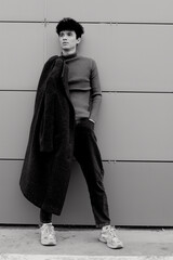 Wall Mural - Fashionable man in coat standing against gray wall in black and white photo