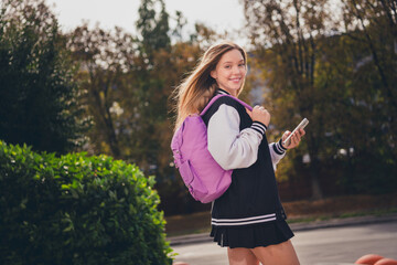 Poster - Photo of pretty dreamy girl dressed bomber short skirt backpack communicating modern device outdoors urban city park