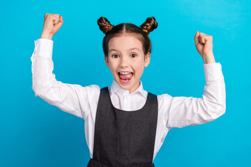 photo portrait of cute little girl raise fists winning dressed stylish school uniform isolated on bl