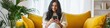 © Andrii Zastrozhnov - A woman is sitting on a yellow couch and looking at her cell phone. She is smiling and she is enjoying herself