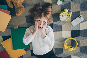 Poster - Photo of charming excited nice funny small boy lying on floor carpet hand face wow school supply sale indoors