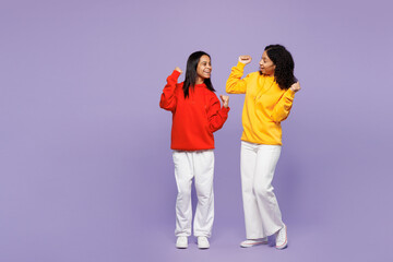 Wall Mural - Full body two young fun little kid teen girls women they wears red yellow hoodie casual clothes doing winner gesture celebrate clenching fists isolated on plain purple background. Lifestyle concept.