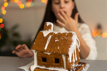 A girl plays with a gingerbread house for traditional Christmas decoration