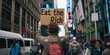© Brian - street protest, activist holding sign 'Eat the Rich' text