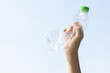© InfiniteFlow - Recyclable plastic bottle held in hand up on sky background. Hand holding plastic waste for recycle reduce and reuse concept to promote clean environment with effective recycling management. Gyre