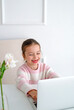 © Maryna - Laughing funny girl in front of a laptop monitor. Children's Online education and development