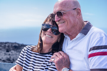 Canvas Print - Cheerful couple of smiling married senior man and woman hug in outdoors looking at camera. Two elderly retirees enjoying travel and vacation