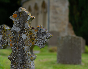 Ancient stone headstone and church in the Cotswolds, England, UK