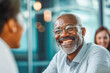 © MVProductions - A mature businessman smiles warmly during a meeting with a younger colleague, sharing his expertise and experience in a modern office setting.