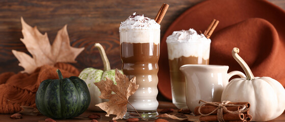 Wall Mural - Glasses of tasty pumpkin latte with cinnamon and almond on wooden background